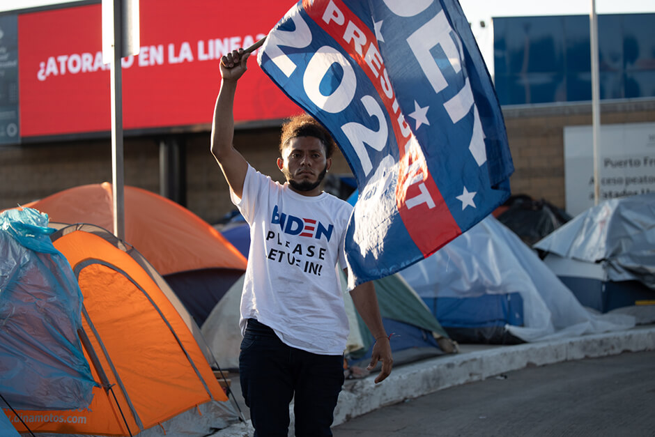 Asylum seeker from Honduras waves his Biden flag at the El Chaparral migrant camp in Tijuana