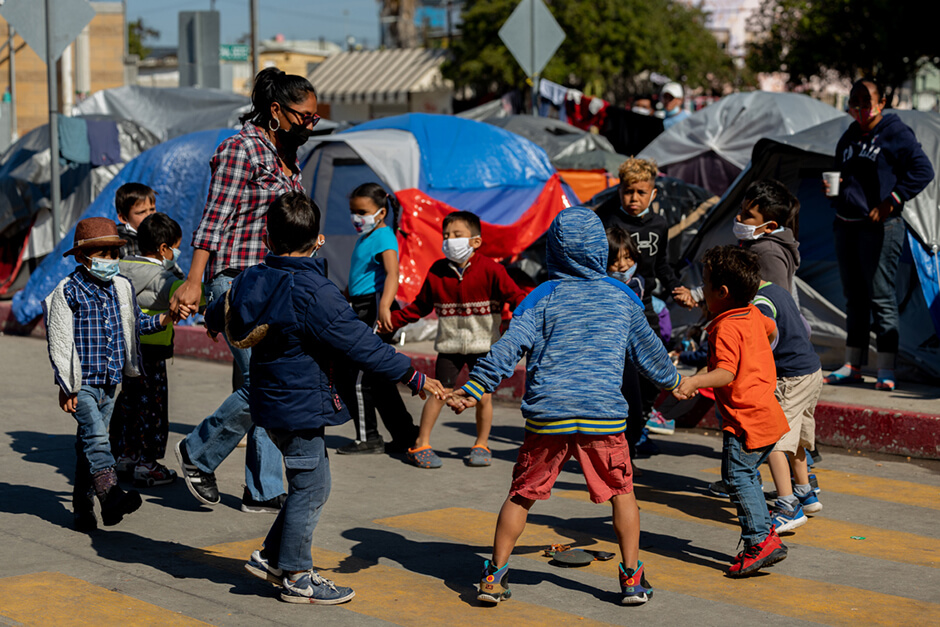 Kids play in the street with teacher at the El Chaparral migrant camp in Tijuana